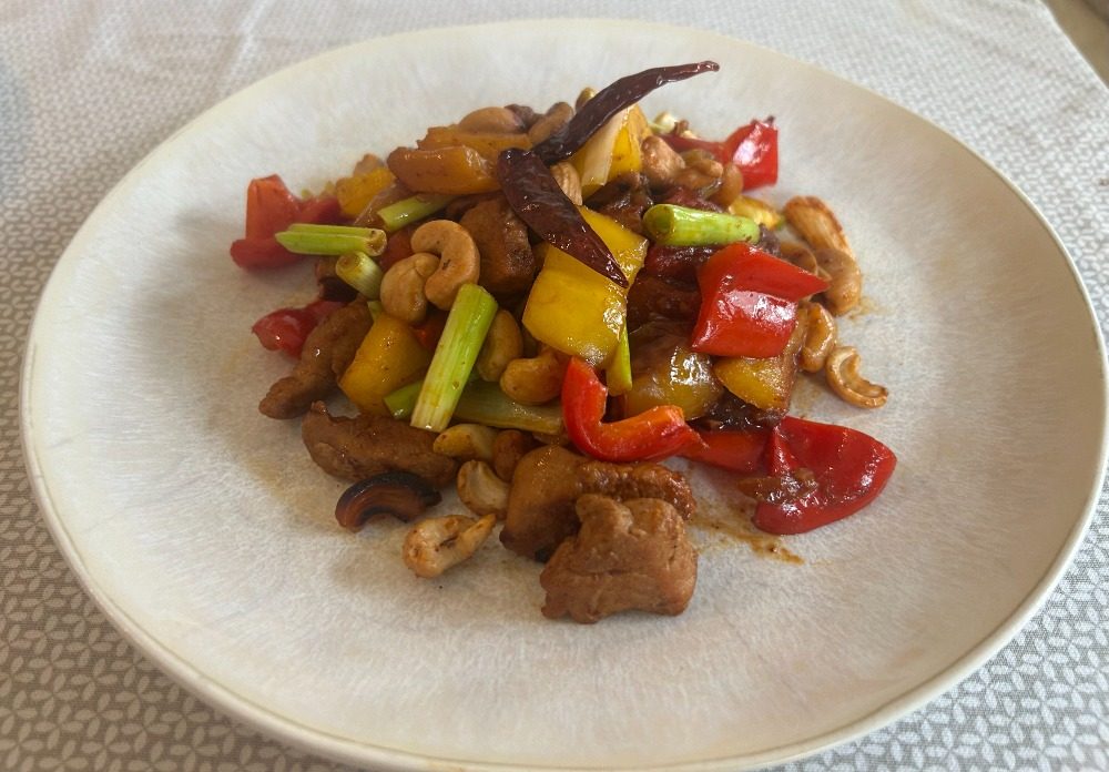Pfannengerührtes Hühnchen mit Cashewkernen, Paprika und getrockneten Chilis auf einem Teller
