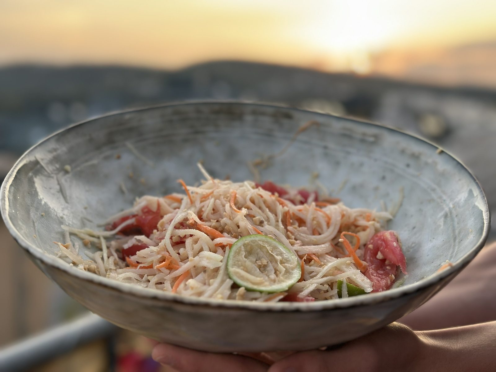 Papayasalat mit Karotte, Tomate, Erdnüssen und Limette in einer Steingutschale